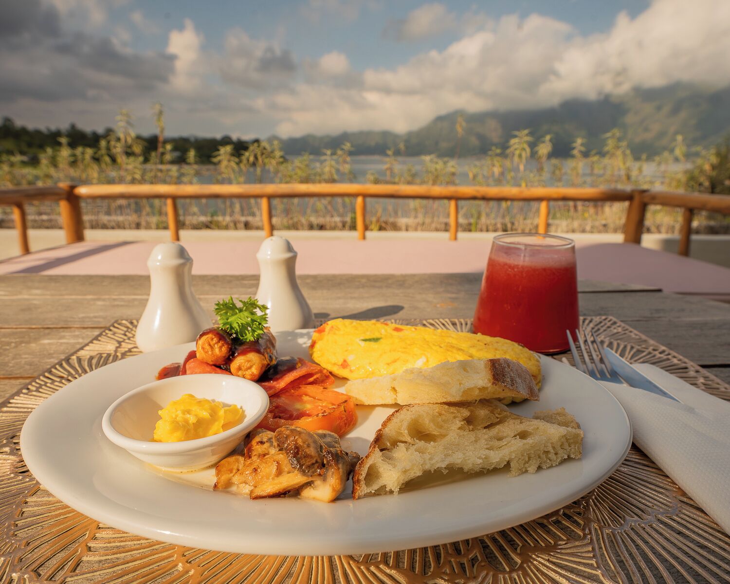 A breakfast plate with eggs, bacon, mushrooms, and toast on a table with a scenic view.