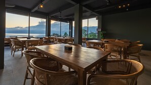 A spacious dining area with large windows offering a view of the sea and mountains. - Tribhuwana Padma Lake Resort (Kintamani)