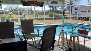 A covered outdoor seating area with chairs and tables, overlooking a swimming pool. - TROPICAL WATERFRONT/POOL  BEACH, BOAT🛥 HOME BY VENICE SIESTA KEYS BEACH PETS OK (Port Charlotte)