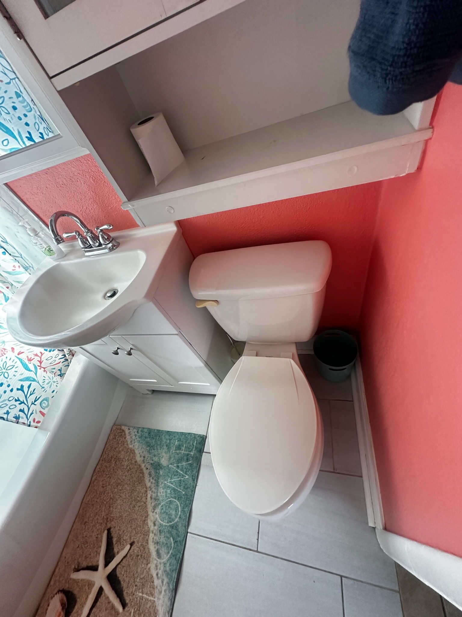 Een badkamer met een wit wastafel, toilet en een kleine prullenbak.