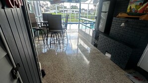 A spacious indoor area with a terrazzo floor, a ceiling fan, and a view of a swimming pool. - TROPICAL WATERFRONT/POOL  BEACH, BOAT🛥 HOME BY VENICE SIESTA KEYS BEACH PETS OK (Port Charlotte)