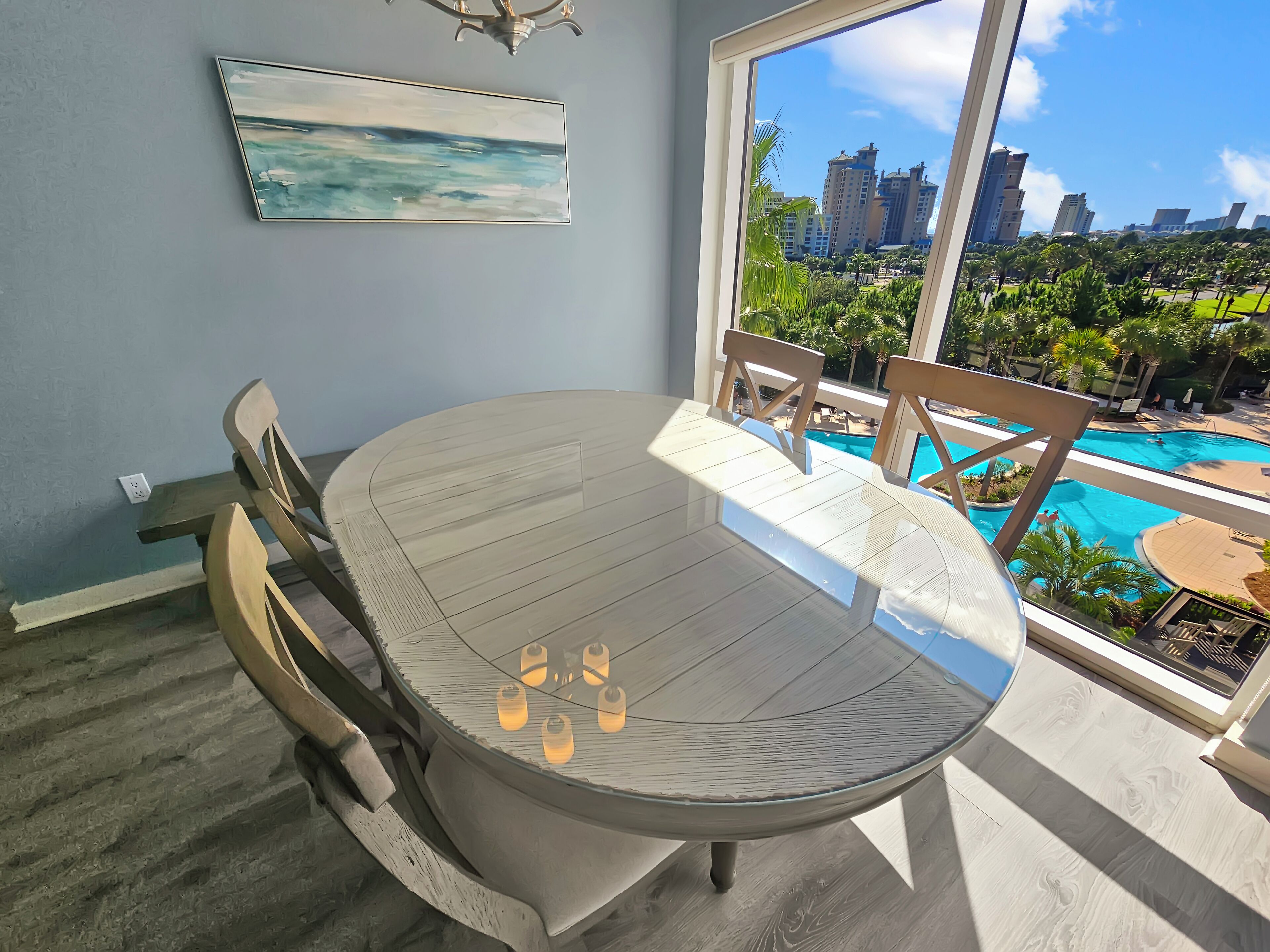 Un espace repas comprenant une table ronde, des chaises et une vue sur une piscine et le paysage urbain.