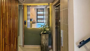 A modern hallway with a wooden panel wall, a reception desk, and a potted plant.