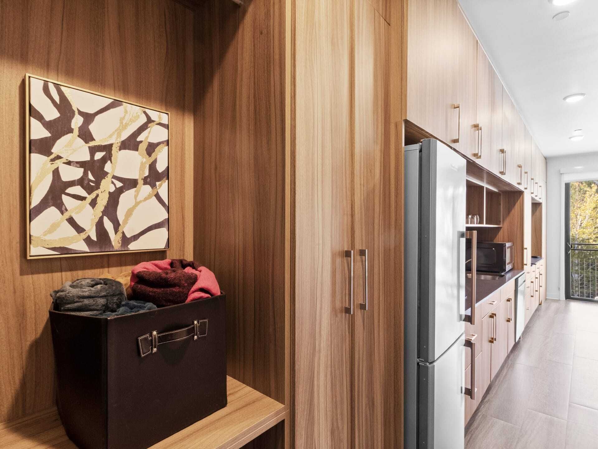 A modern kitchen with wooden cabinetry, a stainless steel refrigerator, and a microwave.