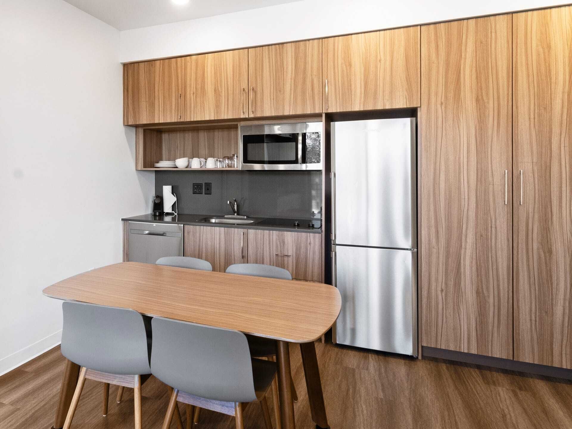 Una cucina moderna con mobili in legno, elettrodomestici in acciaio inossidabile e un'area pranzo con tavolo e sedie.