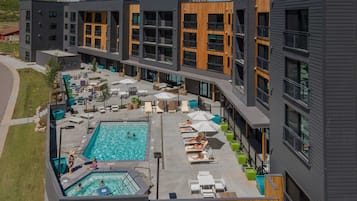 A modern building with a rooftop pool area, outdoor seating, and a clear view of the surrounding landscape.