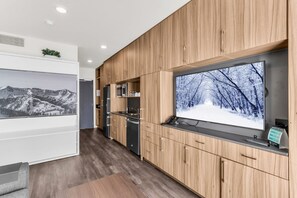 A modern kitchen with wooden cabinetry, a built-in microwave, and a large window with a snowy landscape view.
