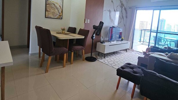 A modern living room with a dining area, a TV, and a balcony with a city view. - Luxury Celebration Apartment - Belém, PA (Belém)