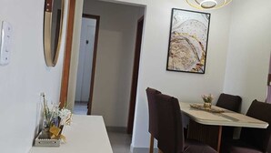 A dining area with a white table, dark chairs, a hanging light fixture, and a framed picture on the wall. - Luxury Celebration Apartment - Belém, PA (Belém)