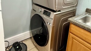 A compact laundry area with stacked washing machines and a robotic vacuum cleaner. - Terrific 3-bedroom apartment in Fairbanks (Fairbanks)