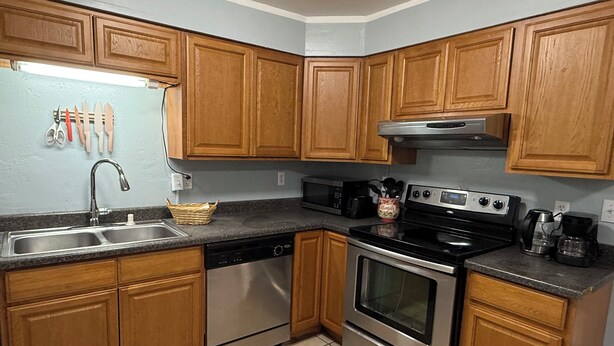 A kitchen with wooden cabinets, stainless steel appliances, a microwave, a coffee maker, and a dish rack. - Terrific 3-bedroom apartment in Fairbanks (Fairbanks)