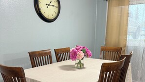 A dining room with a round table, six wooden chairs, a clock on the wall, and a window with curtains. - Terrific 3-bedroom apartment in Fairbanks (Fairbanks)