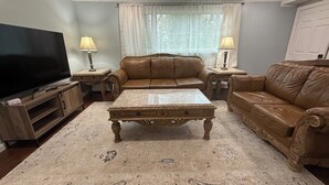 A living room with a brown leather sofa, a coffee table, a TV, and two lamps. - Terrific 3-bedroom apartment in Fairbanks (Fairbanks)