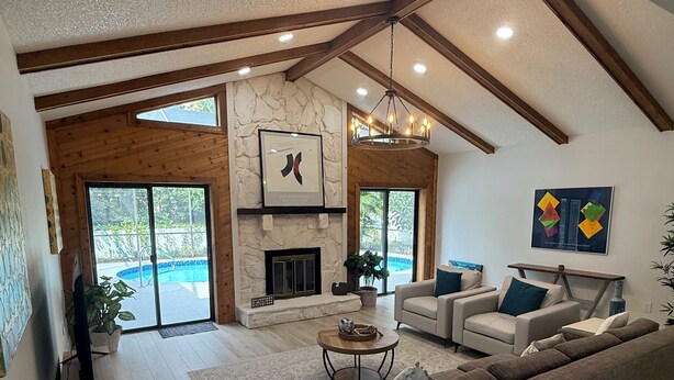 A spacious living room with a fireplace, a large sofa, and a view of a swimming pool.