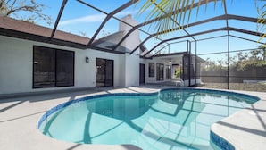 A modern house with a swimming pool, large windows, and a covered patio area.