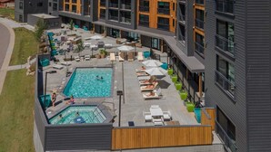 A modern building with a rooftop pool area, outdoor seating, and a clear view of the surrounding landscape.