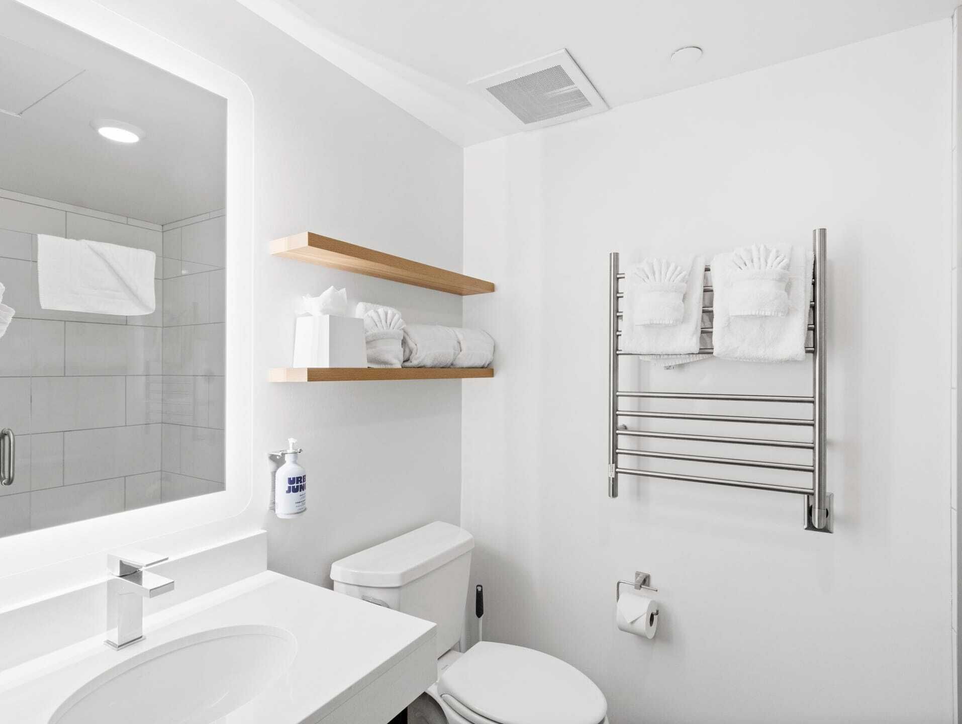 A modern bathroom with a white sink, toilet, and towel rack.