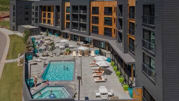 A modern building with a rooftop pool area, outdoor seating, and a clear view of the surrounding landscape.