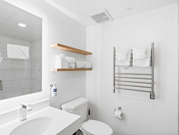 Un baño moderno con lavamanos, inodoro y toallero blancos.