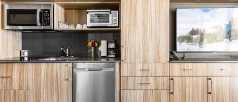 Una cocina moderna con armarios de madera, electrodomésticos de acero inoxidable y un ventanal con vistas a un paisaje nevado.