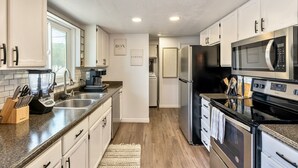 Una cocina moderna con armarios blancos, electrodomésticos de acero inoxidable y encimera de granito.