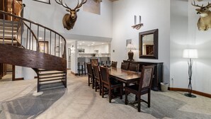 Un coin repas avec une table et des chaises en bois, un lustre et un ventilateur de plafond.
