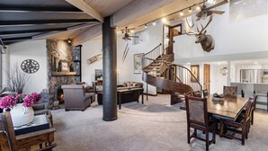 Un vaste espace de vie comprenant un escalier en bois, une table à manger et une cheminée.