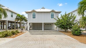 A two-story house with a garage, a covered patio, and a paved driveway.