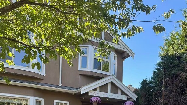 A two-story house with a stone facade, a gated entrance, and a mailbox labeled 8079. - Cozy 1-BR Suite in West Side • Kitchen & Living (Vancouver)