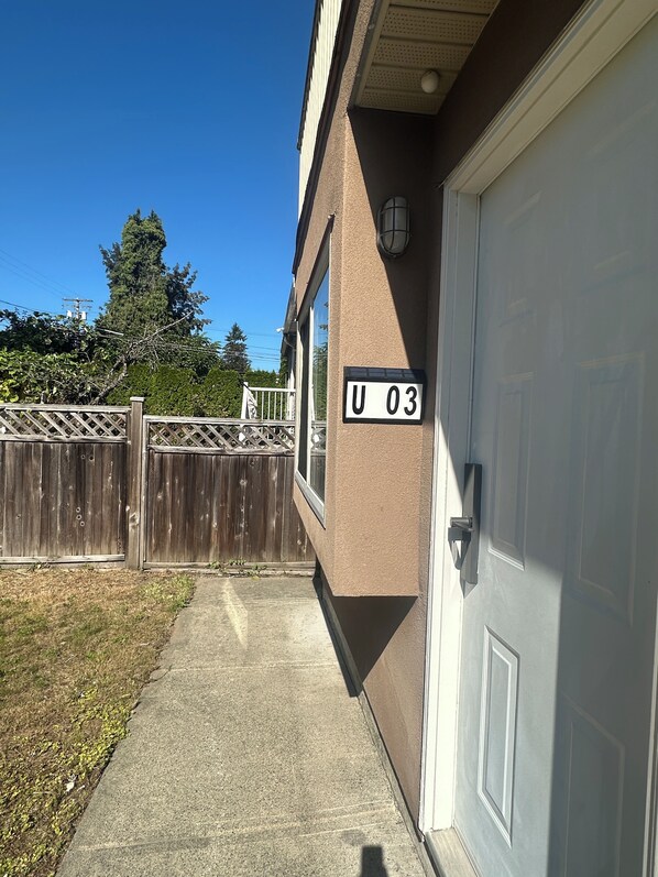 A residential building with a garage door, a wooden fence, and a clear sky. - Cozy 1-BR Suite in West Side • Kitchen & Living (Vancouver)