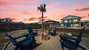 A backyard with a fire pit, blue Adirondack chairs, and a sign reading "S'MORES STATION". - Huge Private Pool | Firepit | Beach One Block Away (gulf shores)