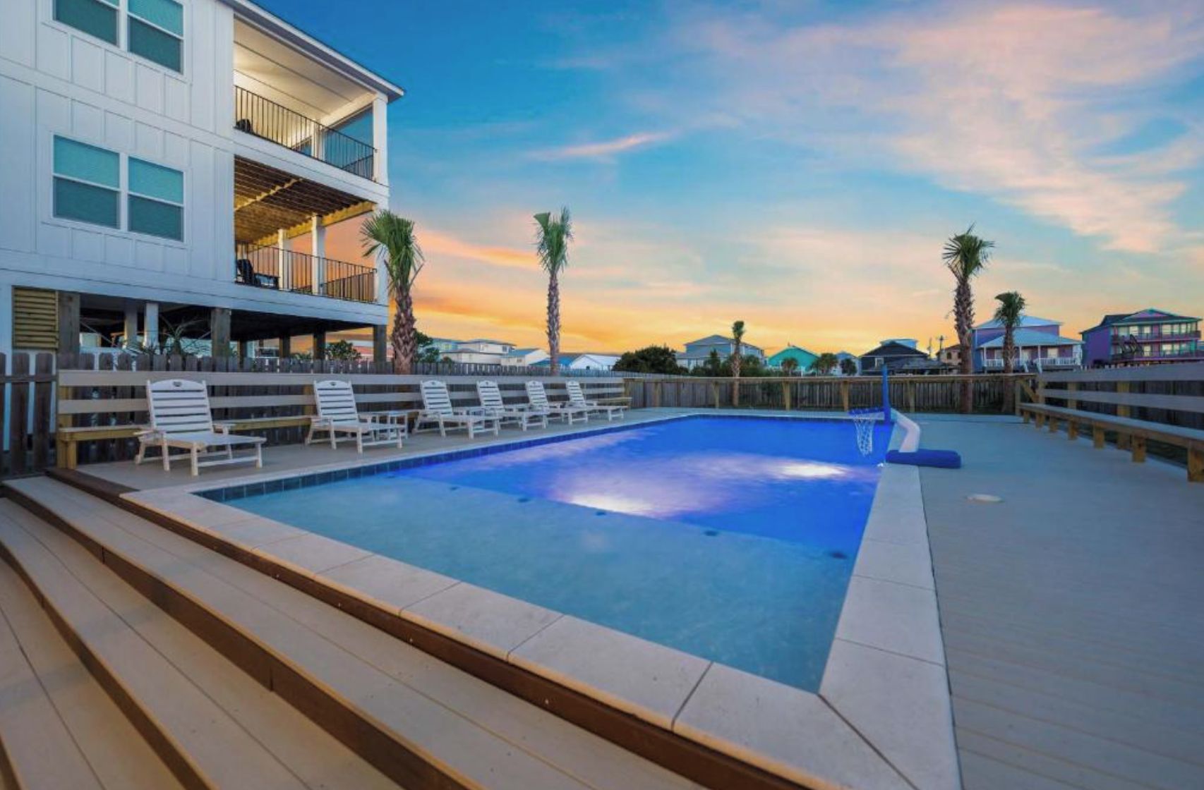 A swimming pool with lounge chairs and a wooden deck.