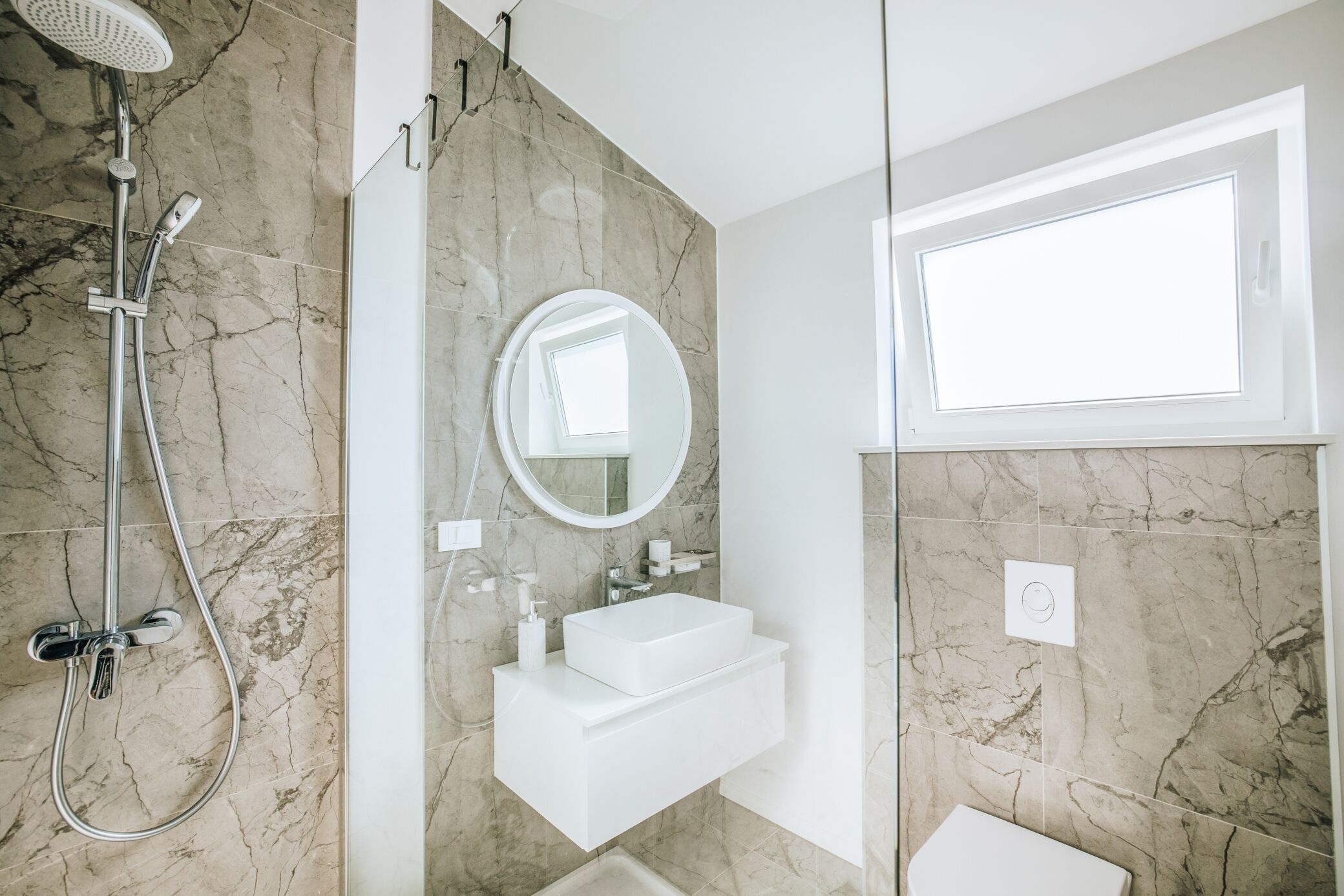 Une salle de bain moderne avec une douche, un lavabo et un miroir.