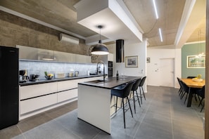 Eine moderne Küche mit einer zentralen Kochinsel, Barhocker und einem Essbereich mit Tisch und Stühlen.