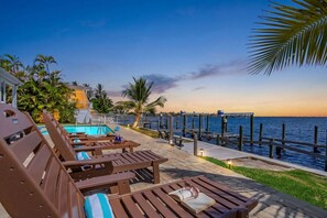 Zona de piscina con sillones de descanso y una piscina, con vista al frente de agua.