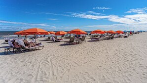 Una playa con filas de sillas de playa y sombrillas naranjas.