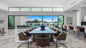 Une salle de conférence spacieuse, dotée d’une grande table et de chaises, offrant une vue sur une piscine et des montagnes, et présentant un aménagement intérieur moderne.