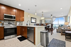A modern kitchen with stainless steel appliances, wooden cabinets, and a central island. - Penthouse with Ocean view from the upper balcony - B314 North Coast Village (Oceanside)