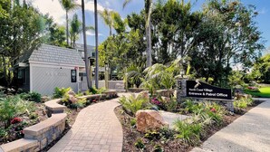 A landscaped entrance with a pathway leading to a building labeled '999 North Coast Village Entrance & Patrol Office.'