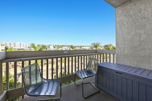 A balcony with two chairs and a view of a residential area.