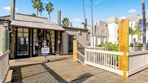 A beachfront property with a wooden deck, a gated entrance, and a sign indicating a key drop-off point.