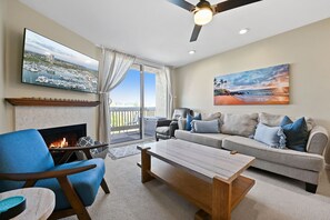 Una sala de estar con chimenea, un sofá, una mesa de centro y un televisor montado en la pared.