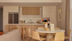 Una cuina moderna amb una illa central, armaris de fusta i un frigorífic d'acer inoxidable.