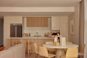 Een moderne keuken met een centraal eiland, houten kastjes en een roestvrijstalen koelkast.