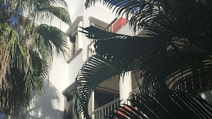 Un edificio blanco con balcones y palmeras.