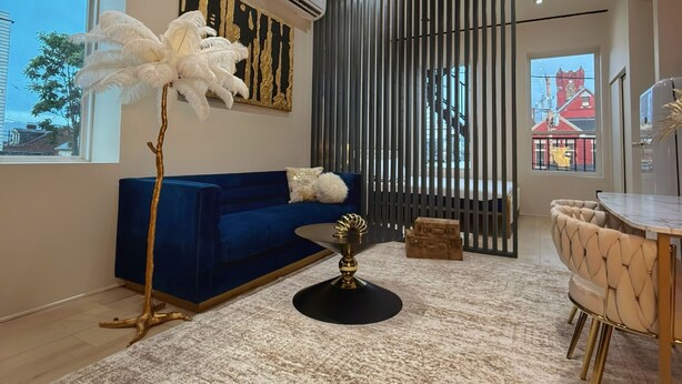 A modern living room with a blue sofa, a round coffee table, and a tall white feathered floor lamp.