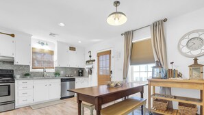 Una cocina moderna con armarios blancos, una mesa de comedor de madera y un banco.
