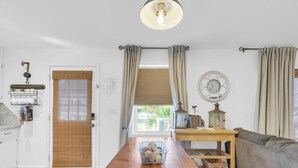 Un amplio espacio de sala con una mesa de madera, un sofá y una ventana con cortinas.