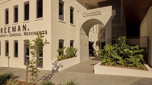 A building with a sign reading 'Cordelia' and another sign for 'Freeman General Merchants.' There are planters with greenery in front of the building.