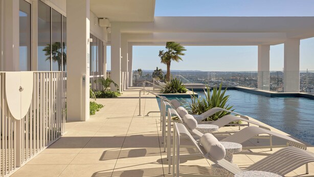 A rooftop pool area with lounge chairs and a view of the city.